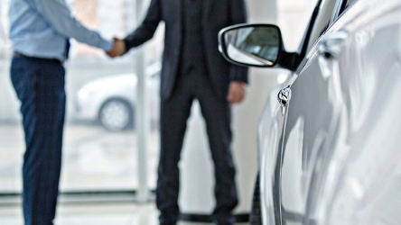 Car salesman shaking hands with customer