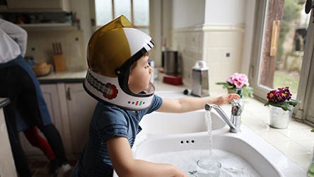 young boy using kitchen faucet